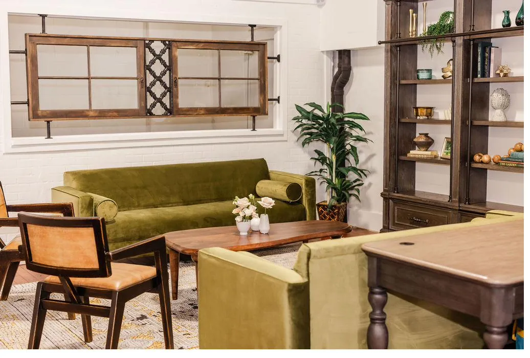 Brick and Beam Events lounge area with green velvet sofa, wood shelving, and vintage-style decor