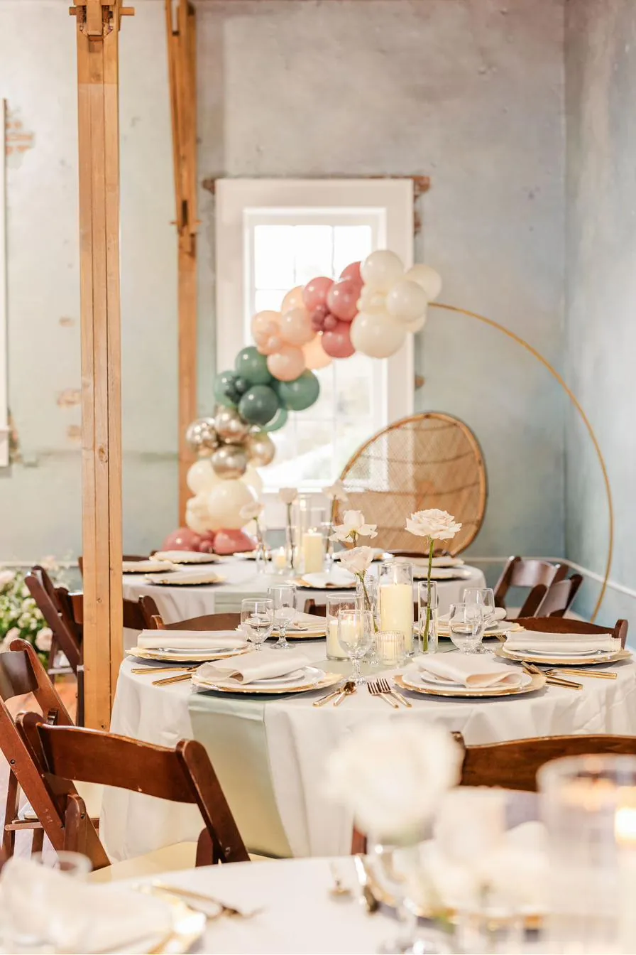 Brick and Beam Events set for a celebration with balloon arch, gold hoop, and round tables with blush roses