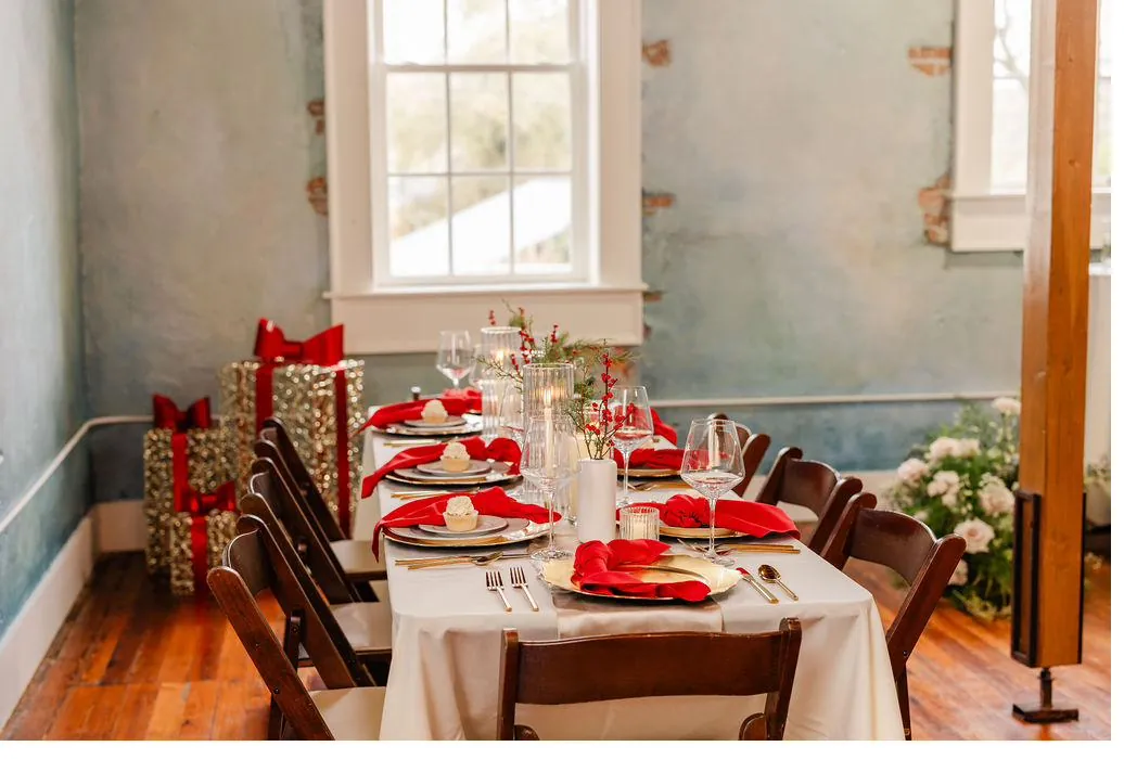 Holiday dinner table at Brick and Beam with red napkins, gold chargers, and festive décor against blue-gray plaster walls