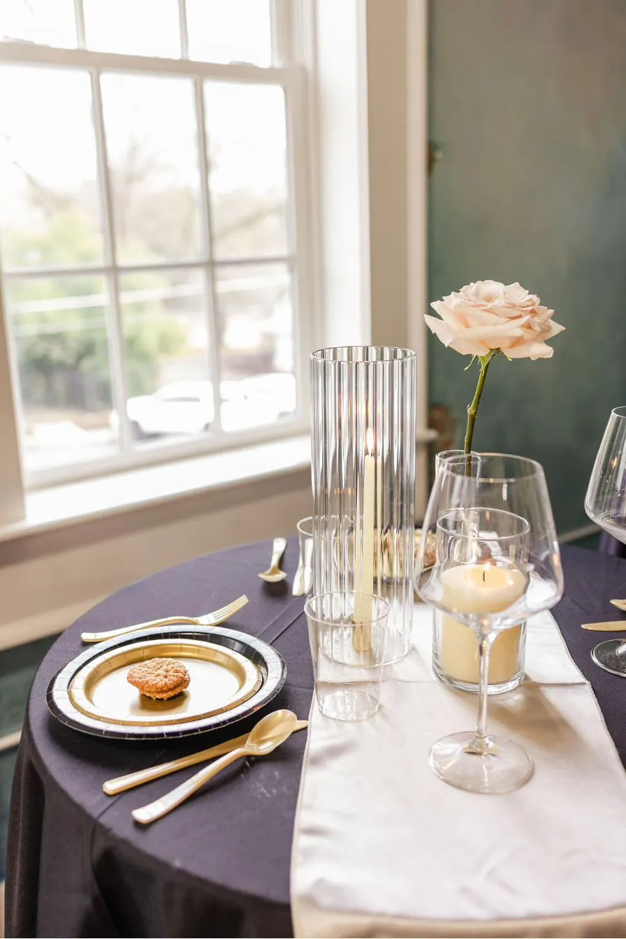 Intimate dinner table at Brick and Beam with single blush rose, candlelight, and deep navy linen