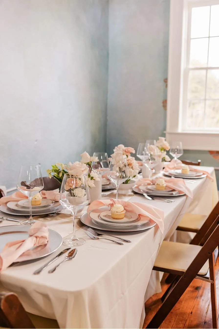 Bridal shower table at Brick and Beam with blush ribbon napkins, pink carnations, and cupcakes